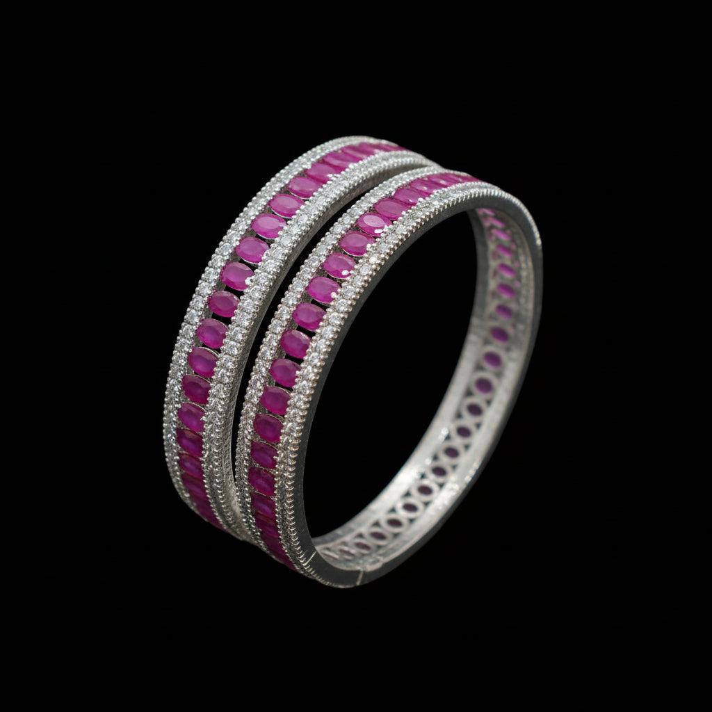 Silver bangles with pink stones on a gray background