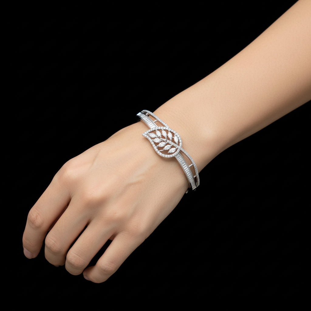 Silver leaf-shaped bracelet on a gray cushion with a dark background