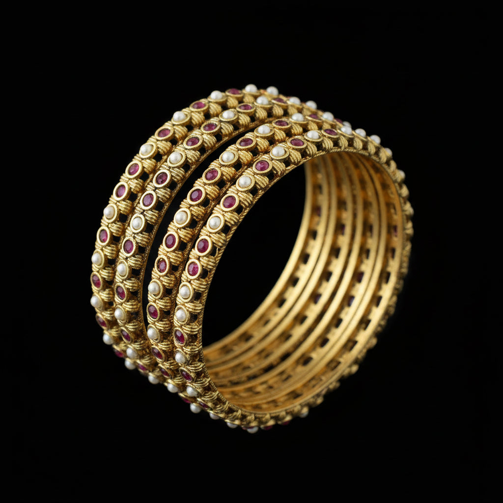 Gold bangles with red stones on a gray stand, branded 'Saheli'.