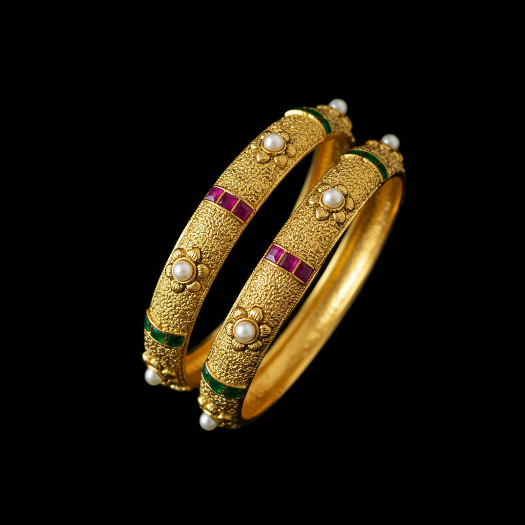 Gold bangles with red and green accents on a gray stand, featuring the brand 'SAHELI'.