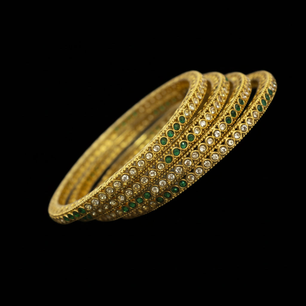 Gold bangles with green and white stones on a dark background, featuring the brand 'Saheli'.