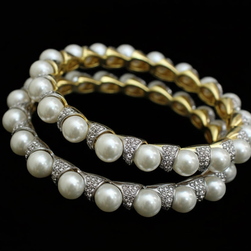 Pearl bangles with gold accents on a black stand, branded 'SAHELI'.