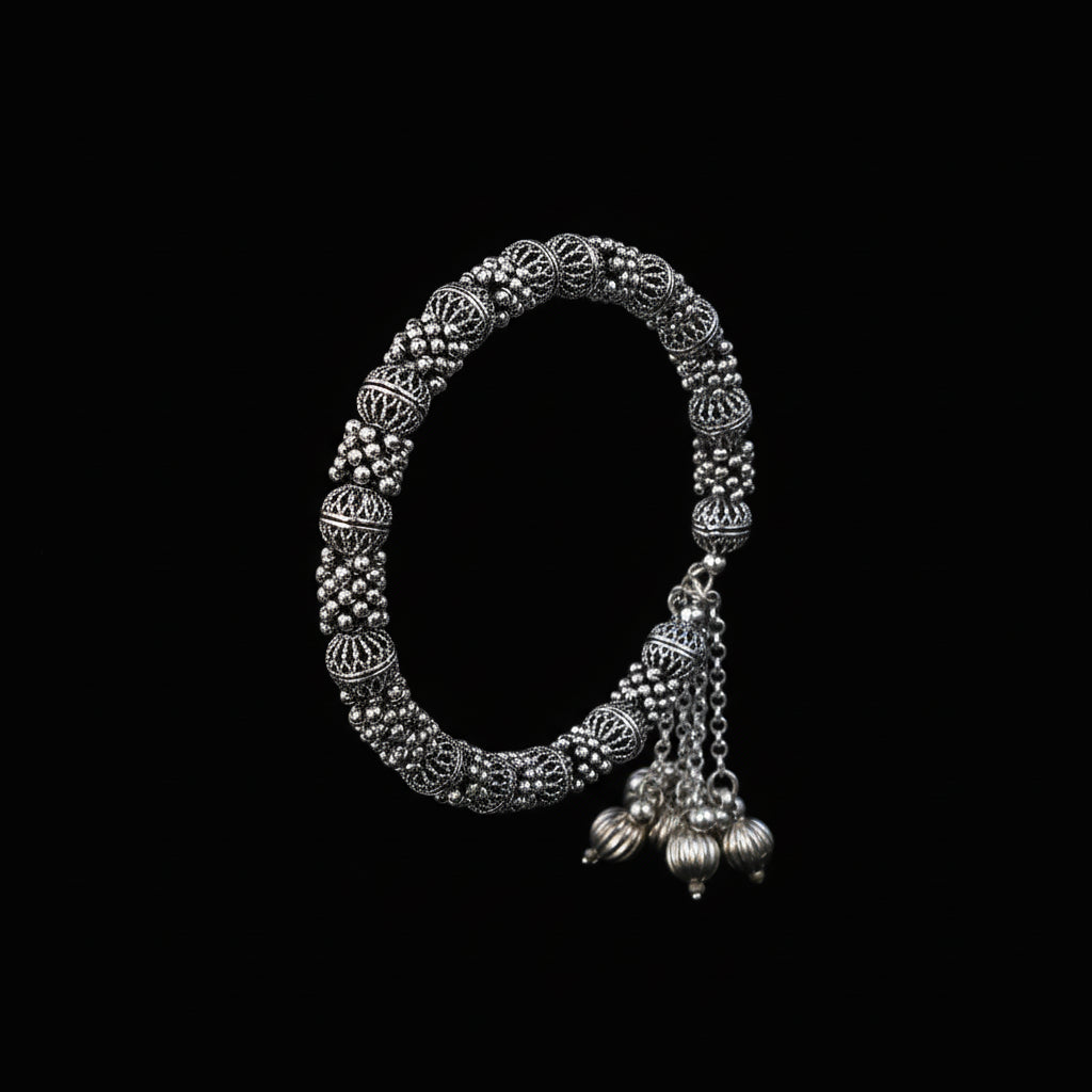 Silver bangles with jhumkas on a black background, featuring the brand 'Saheli'.