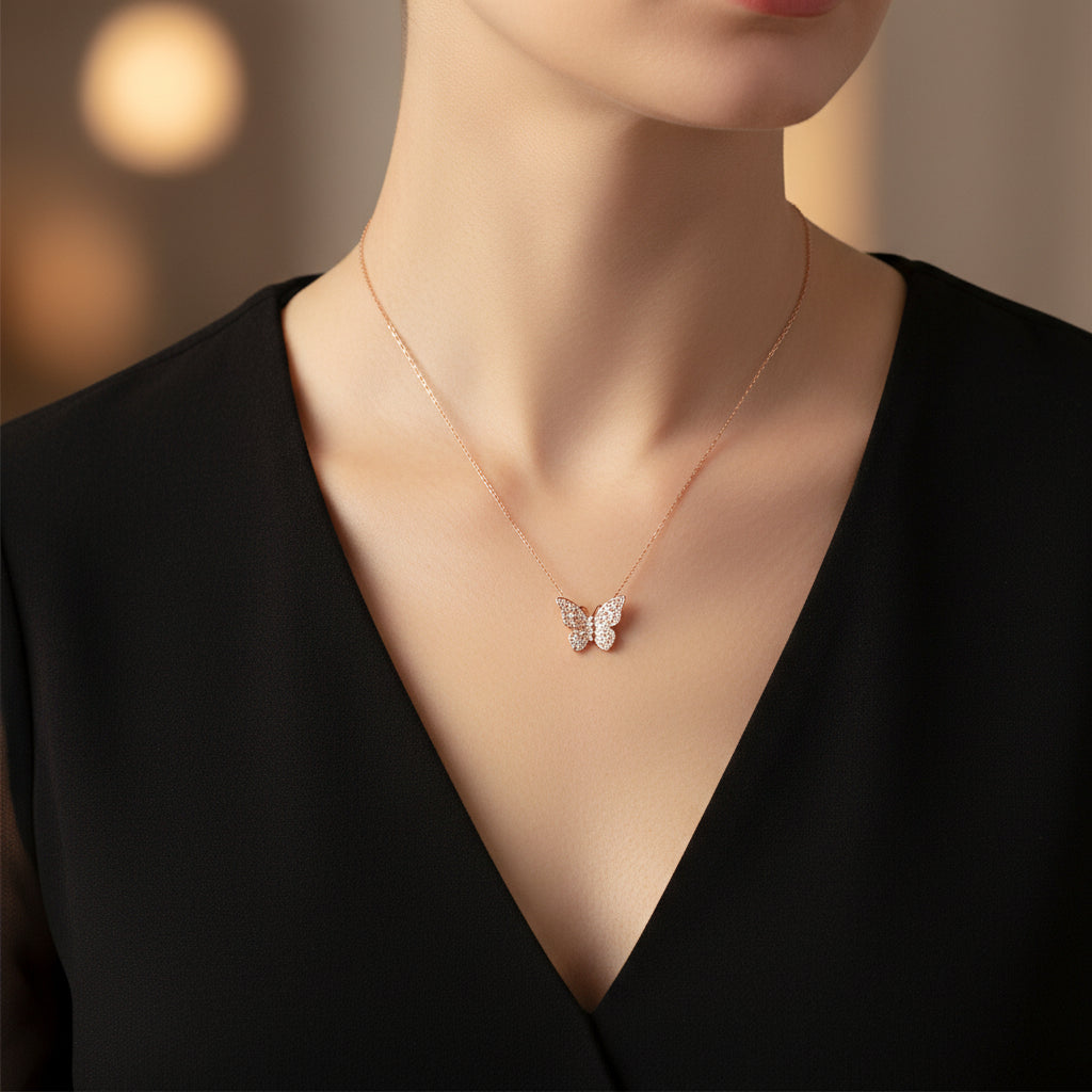 Rose gold necklace with a butterfly pendant on a white card with 'A.B.N.' branding against a black background.
