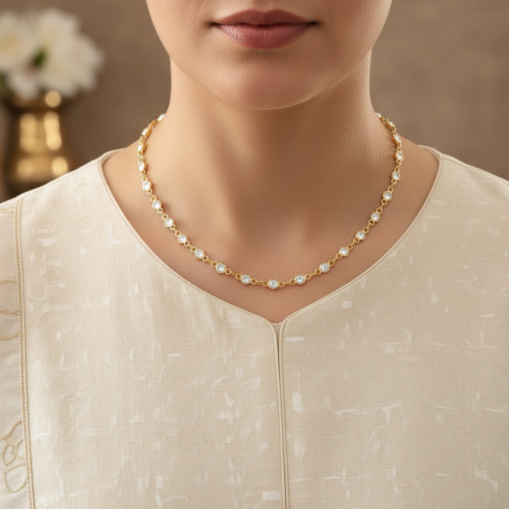 Gold chain necklace with small pearls on a dark background, featuring the brand 'Saheli'.