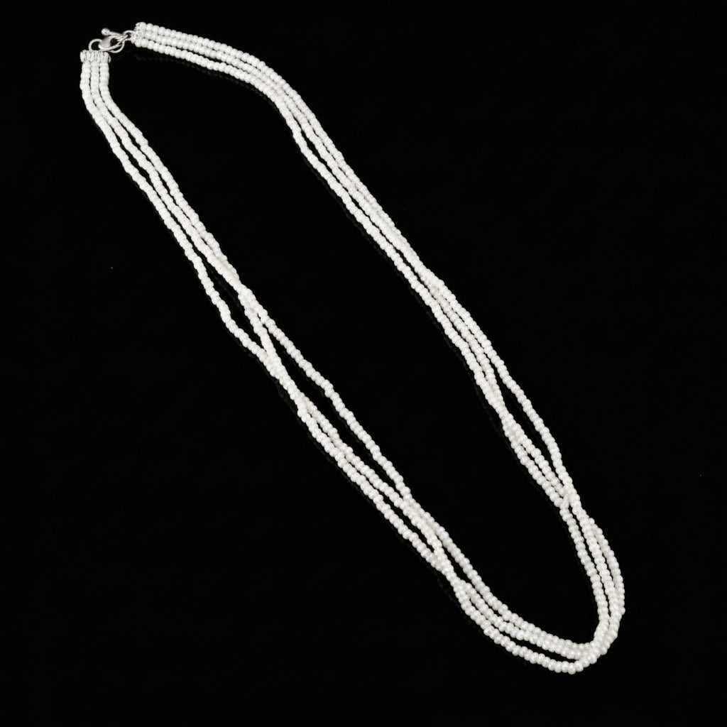 White beaded necklace on a gray background with 'Saheli' branding.