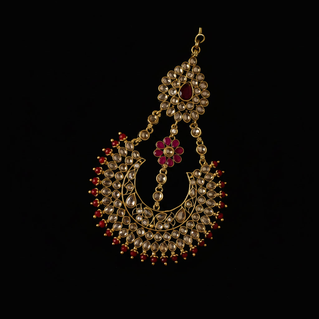 Ornate gold necklace with red and clear stones on a dark background, branded 'Saheli'.