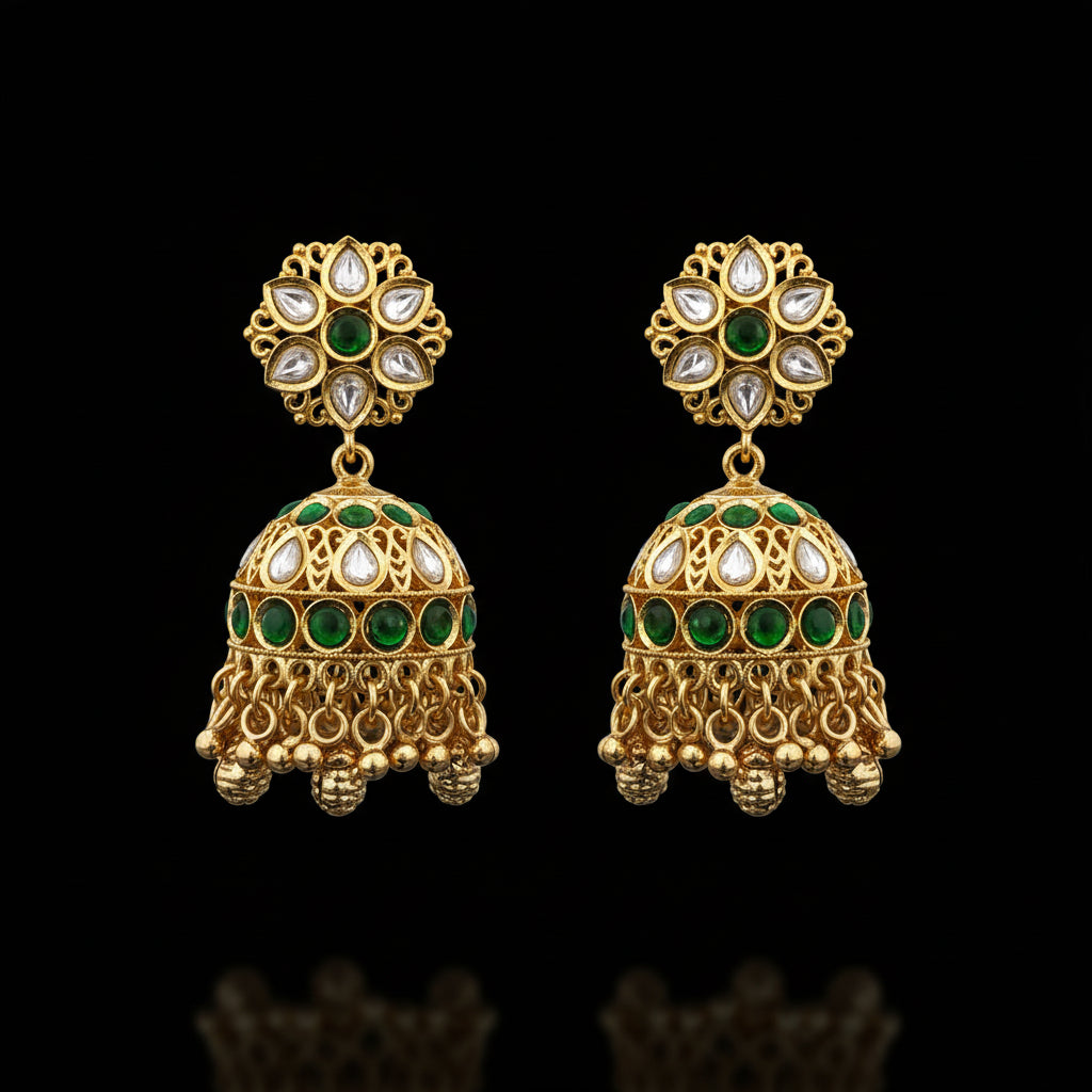 Gold earrings with green and white stones held by a hand against a white background.