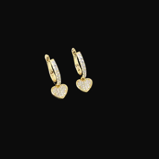 Gold heart-shaped earrings on a dark background