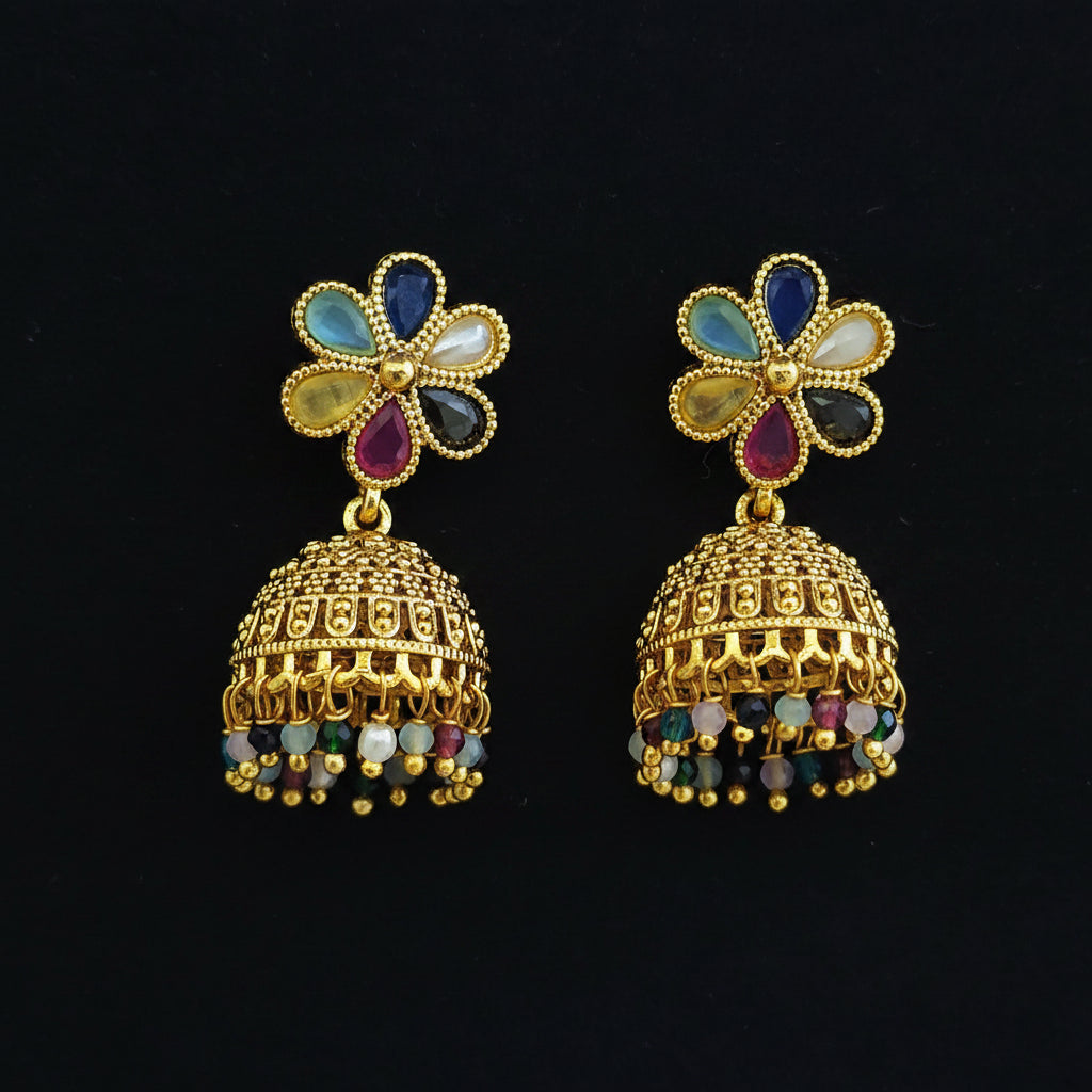A pair of gold-plated Indian jhumka earrings with multicolor enamel flower studs and dangling beaded bells, displayed on a textured blue background.