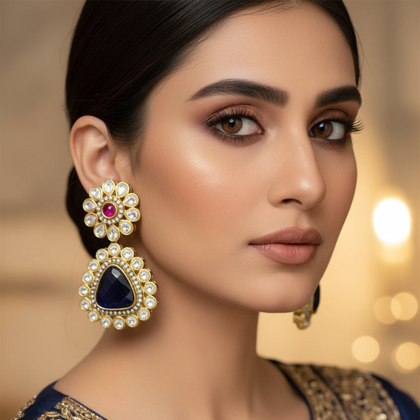 Pair of ornate earrings with black stones and pink gemstones on a dark background