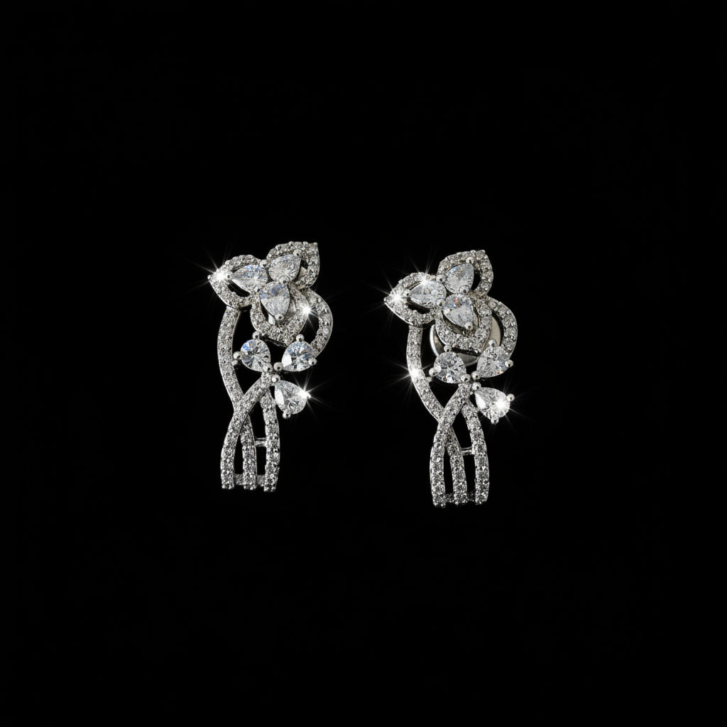 Silver floral earrings on a dark stand with 'SAHELI' branding.