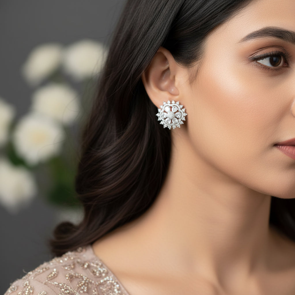 Pair of silver floral earrings on a gray cushion with a dark background