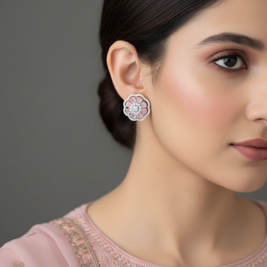 Pair of pink floral earrings with silver detailing on a gray surface.