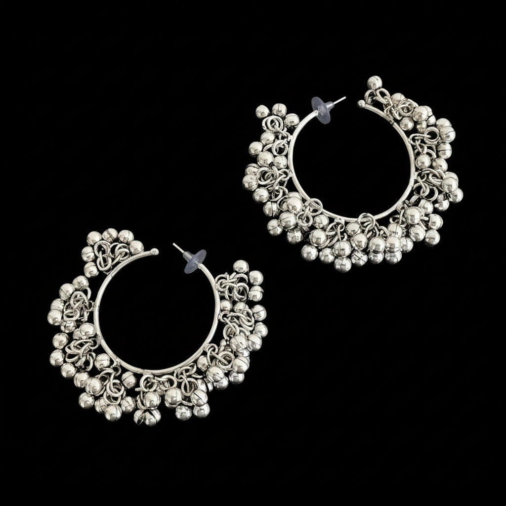 Silver hoop earrings with intricate designs on a dark background, featuring the brand 'Saheli'.