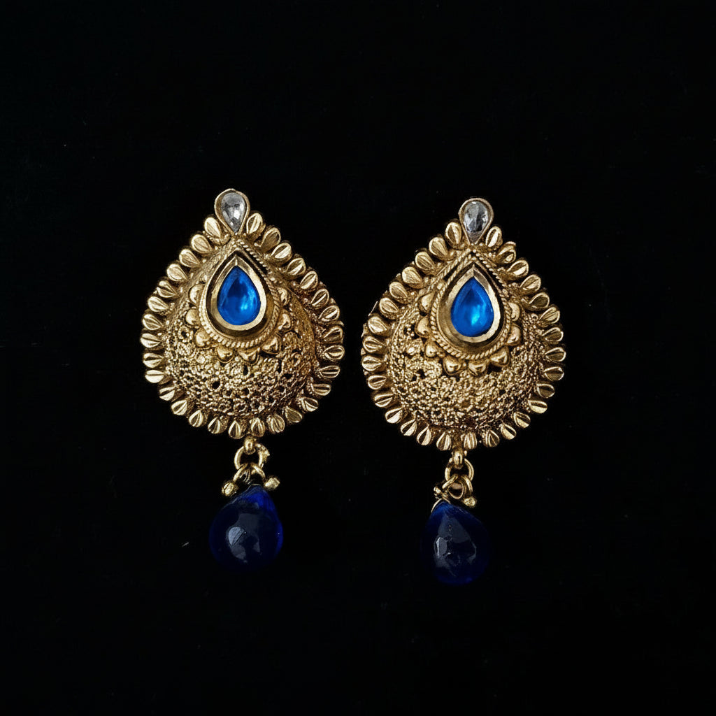 Gold earrings with blue stones on a black background, featuring the brand 'Saheli'.