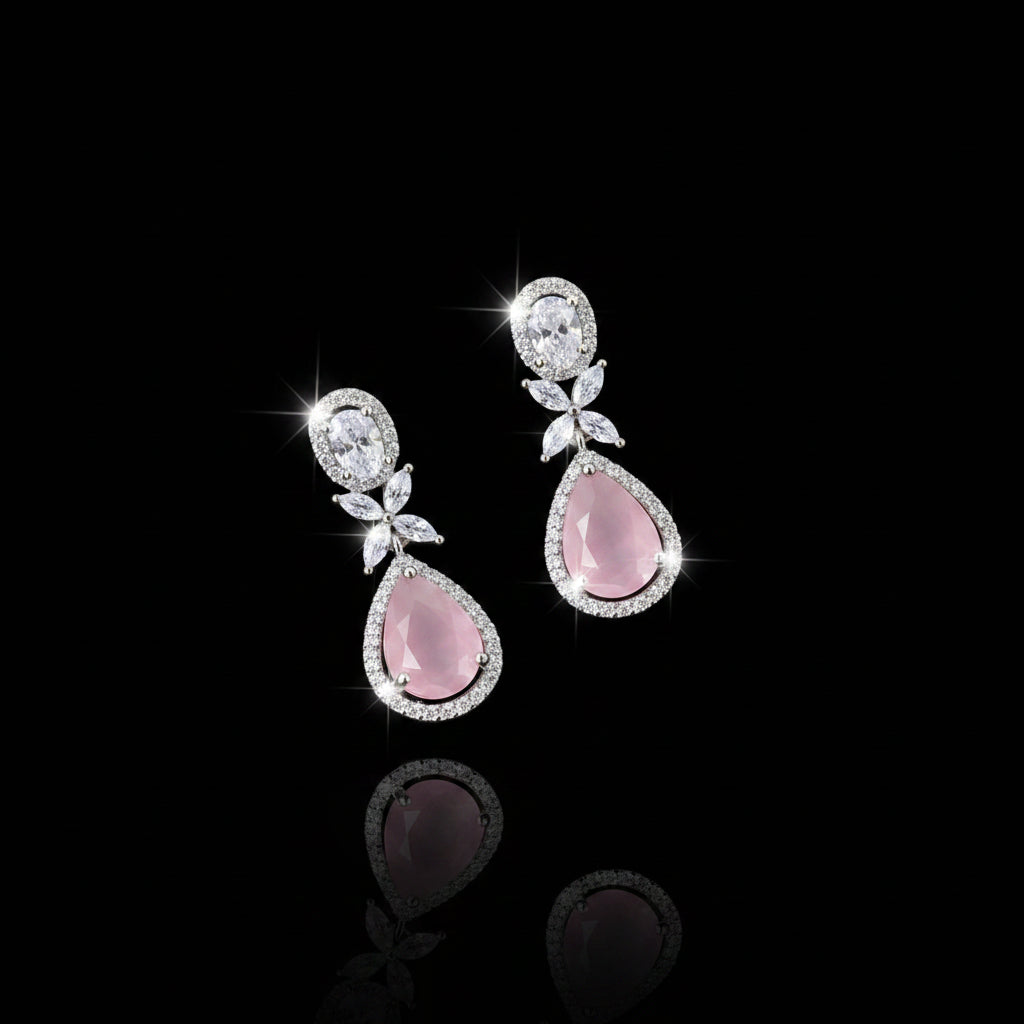 Pair of earrings with pink teardrop stones and silver accents on a dark background