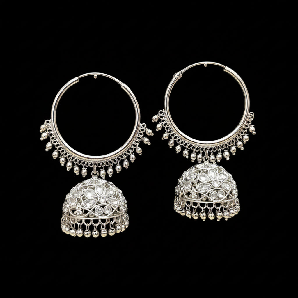Silver hoop earrings with dangling parts on a black stand, branded 'Saheli'.