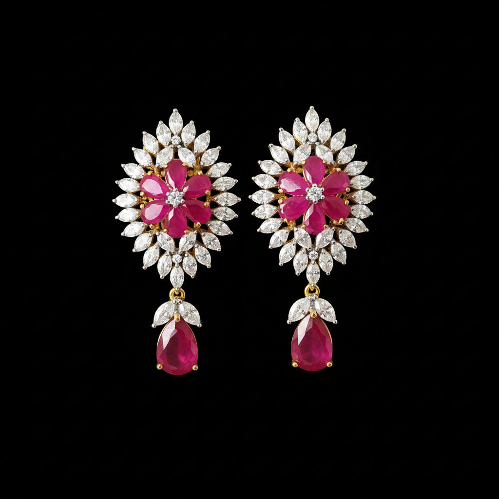 A pair of gold-plated earrings with bright pink gemstone centers, surrounded by clear marquise-cut stones, with teardrop-shaped pink gemstones hanging below, displayed on a black stand against a gray background. The brand logo 'SAHELL MY BEST FRIEND' is visible at the top.