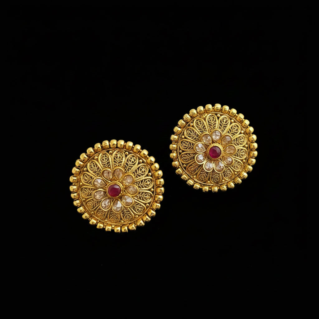 Pair of gold earrings with red gemstones on a dark surface