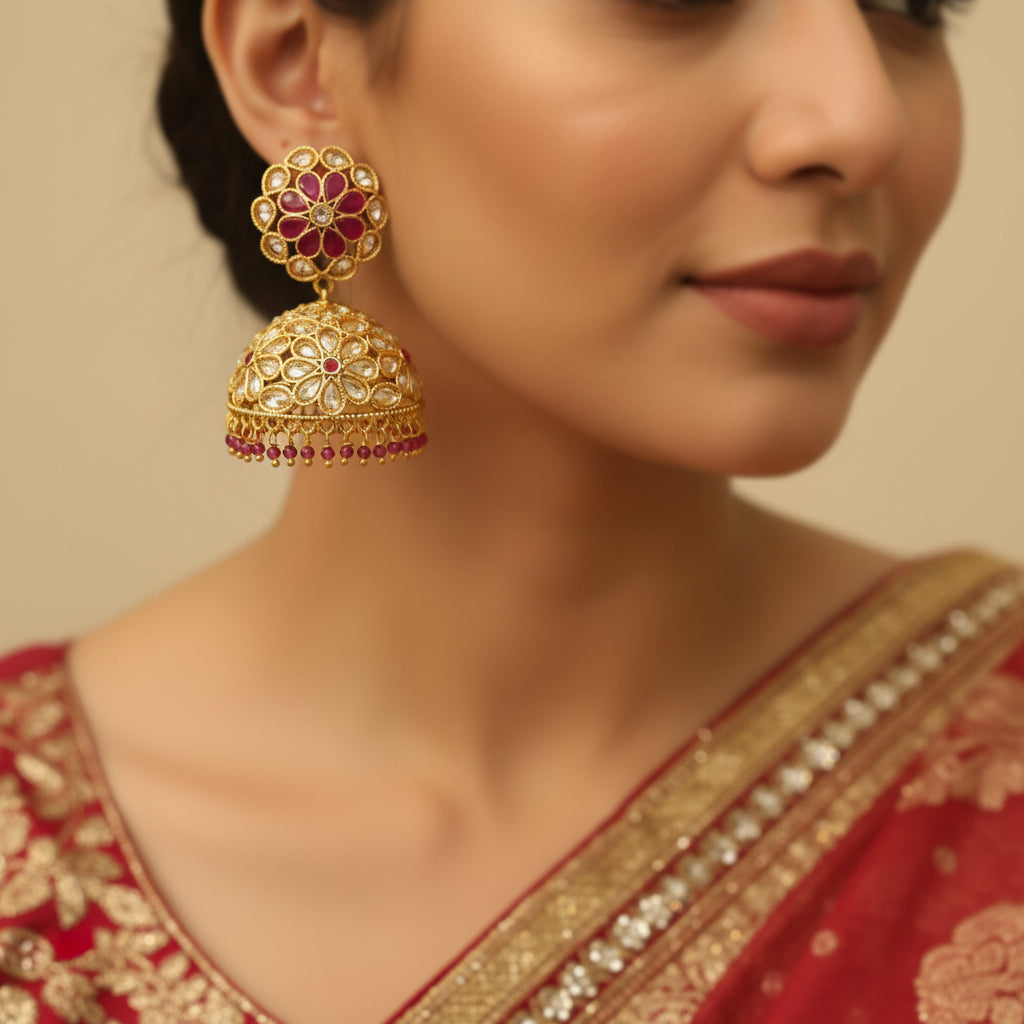 Gold and red earrings on a gray stand with a blurred background