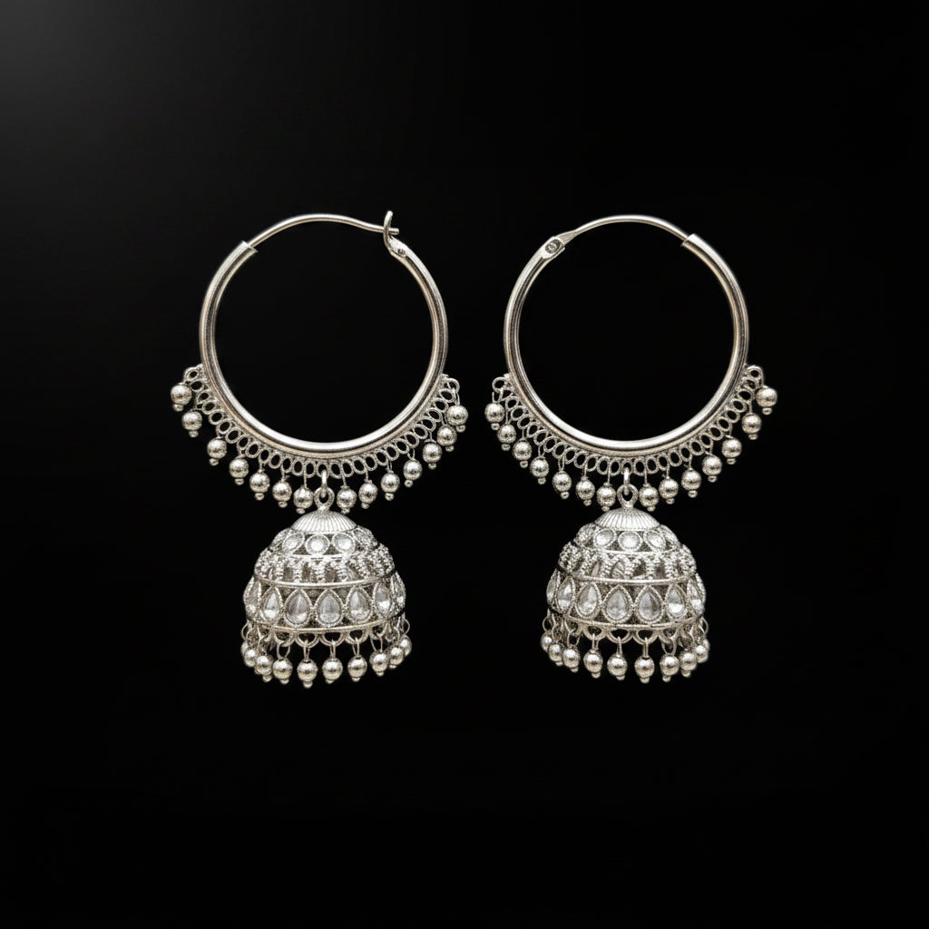 Pair of silver hoop earrings with dangling jhumkas on a black stand.