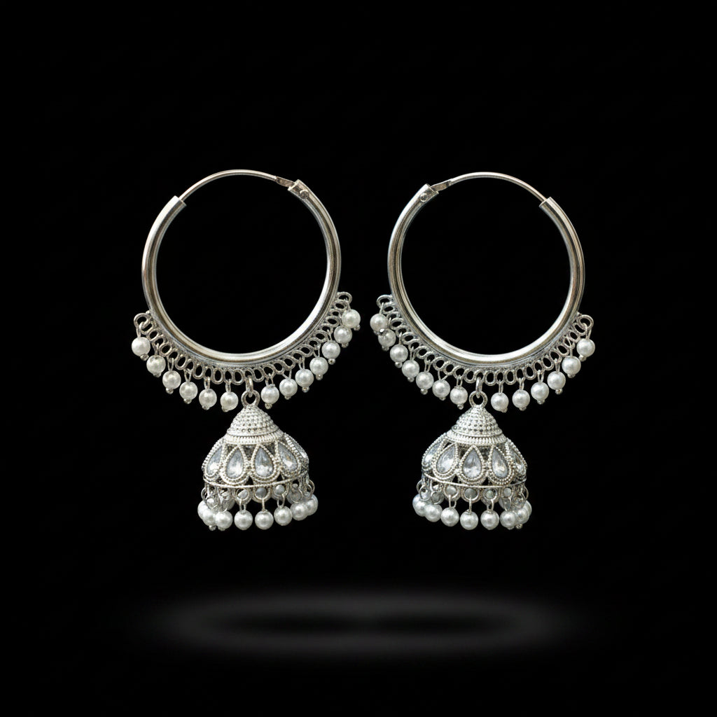 Silver hoop earrings with pearl accents on a black stand against a gray background