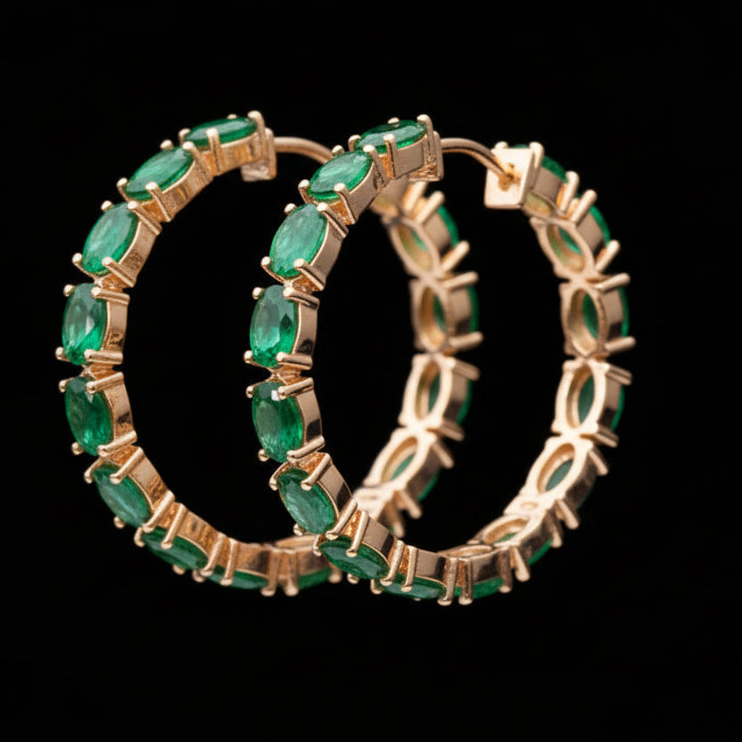 Gold hoop earrings with green gemstones on a black background