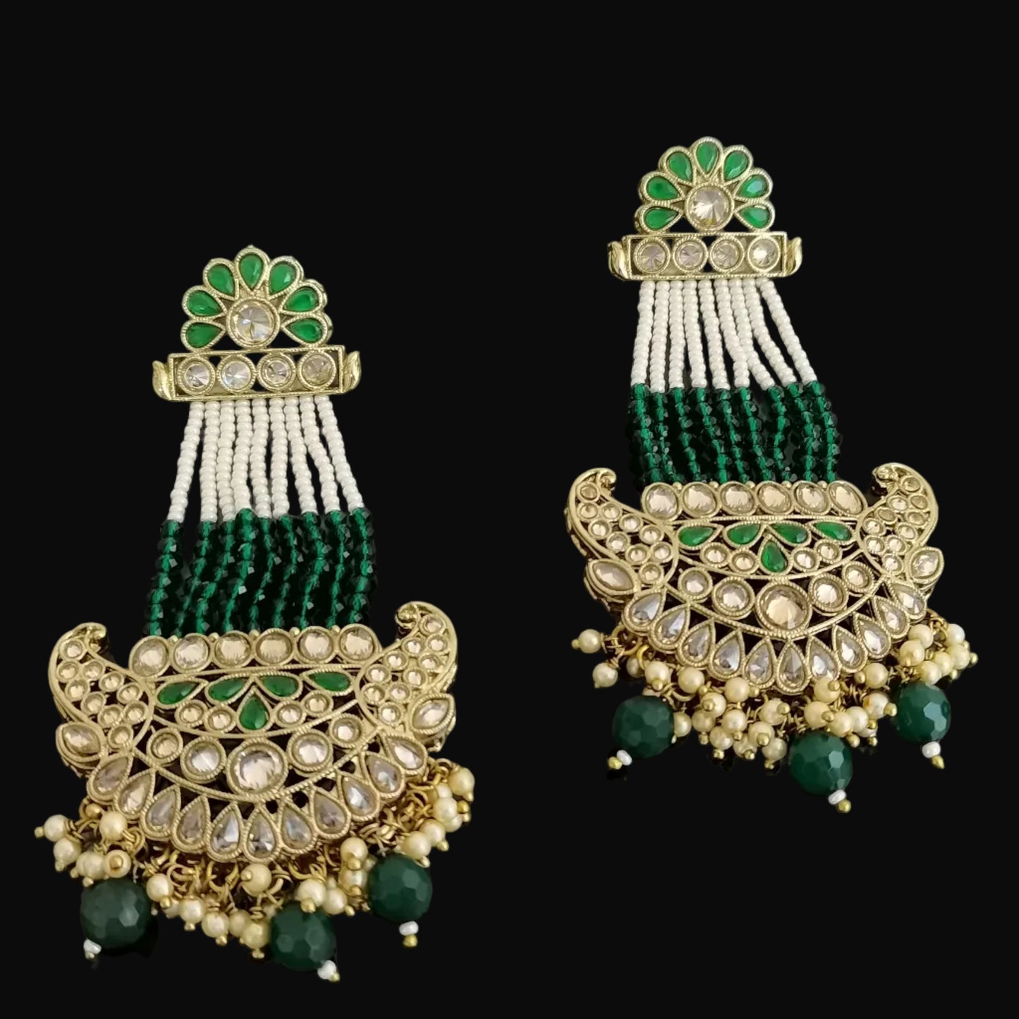 Pair of ornate earrings with green and gold details on a dark background