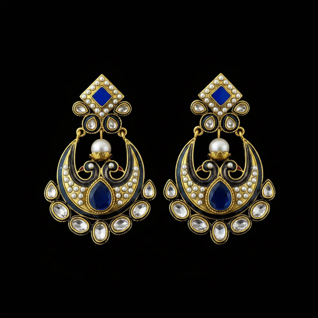 A pair of traditional Indian gold-plated chandelier earrings with blue enamel, white pearl accents, and clear stone embellishments, displayed on a dark reflective surface with the brand name 'SAHELI MY BEST FRIEND' printed above.