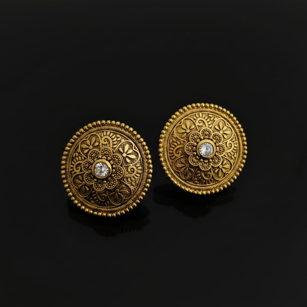 Pair of gold earrings with intricate designs on a black background