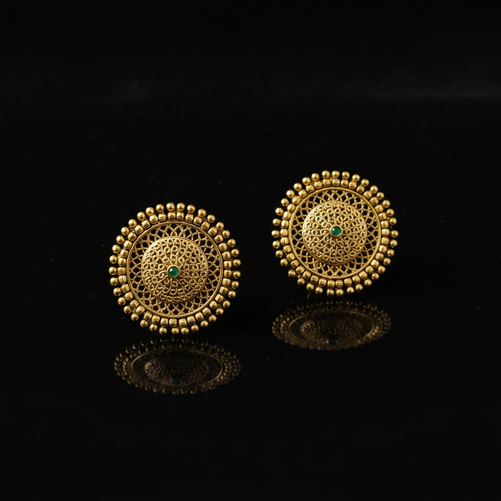 Pair of gold earrings with intricate design on a dark background