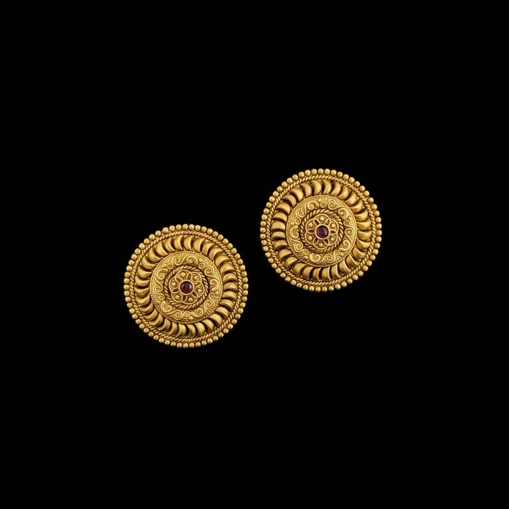 Pair of gold earrings with intricate design on a dark background