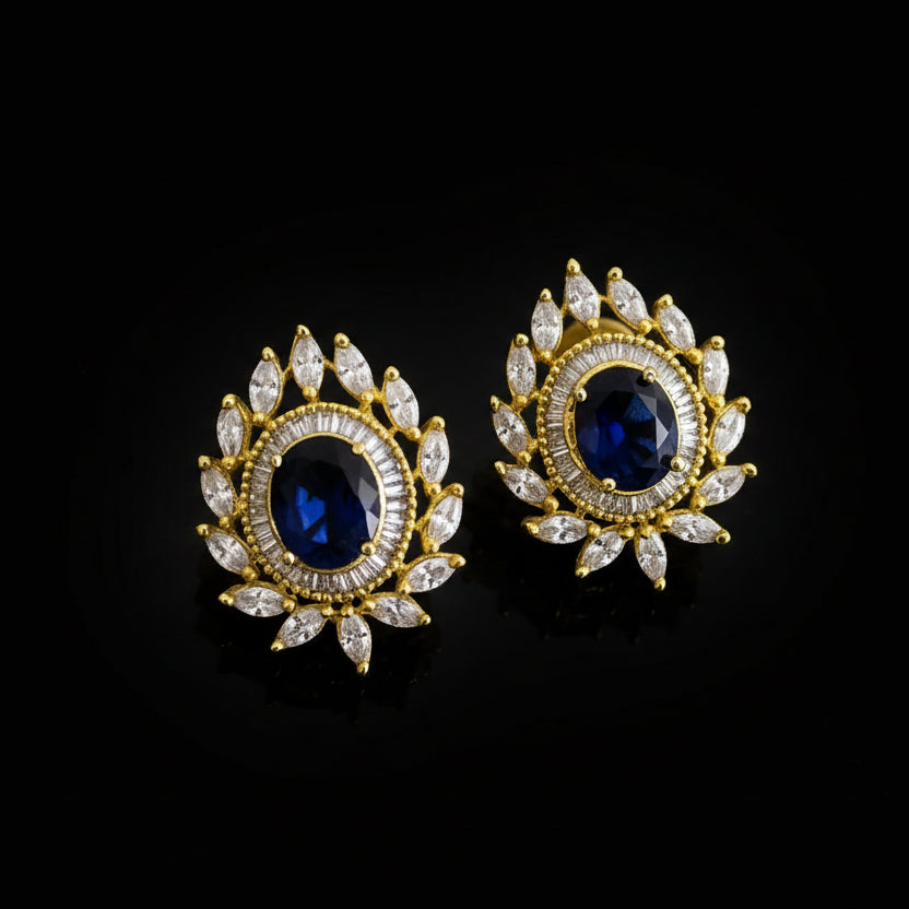 Gold and black earrings with 'Saheli' branding on a gray background
