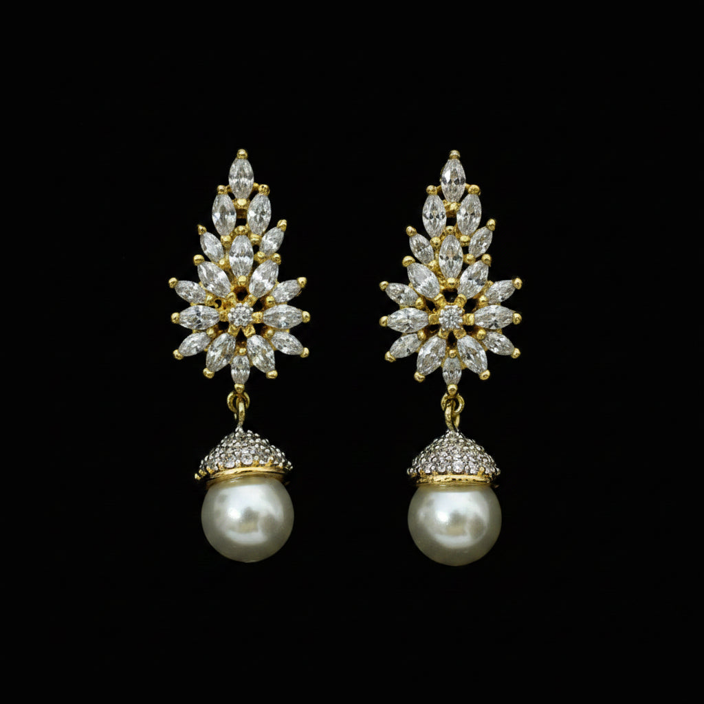 A pair of gold-plated drop earrings with clear crystal starburst designs and white pearl drops, displayed on a black velvet surface with a white brand tag reading 'SAHELL MY BEST FRIEND'.