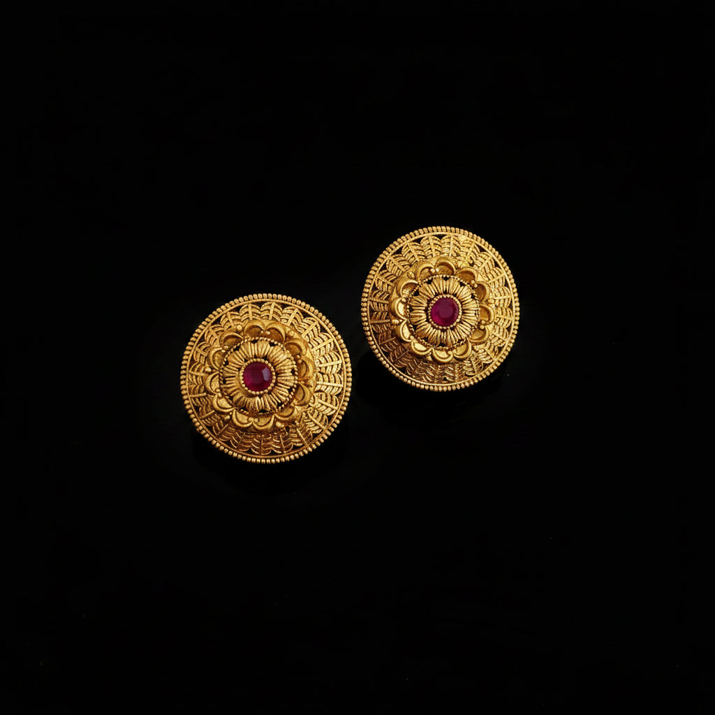 Pair of gold earrings with red gemstones on a black background