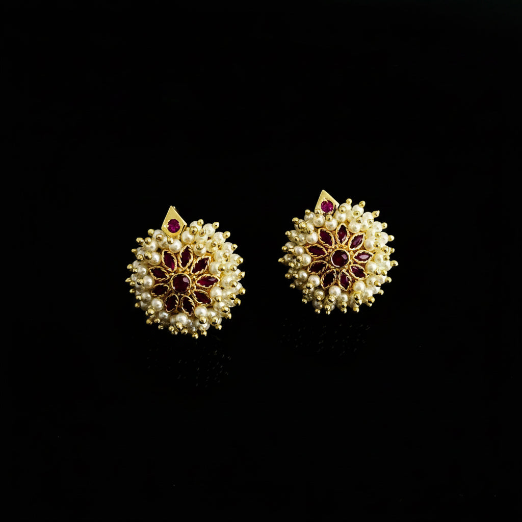 Pair of gold earrings with red gemstones on a dark background