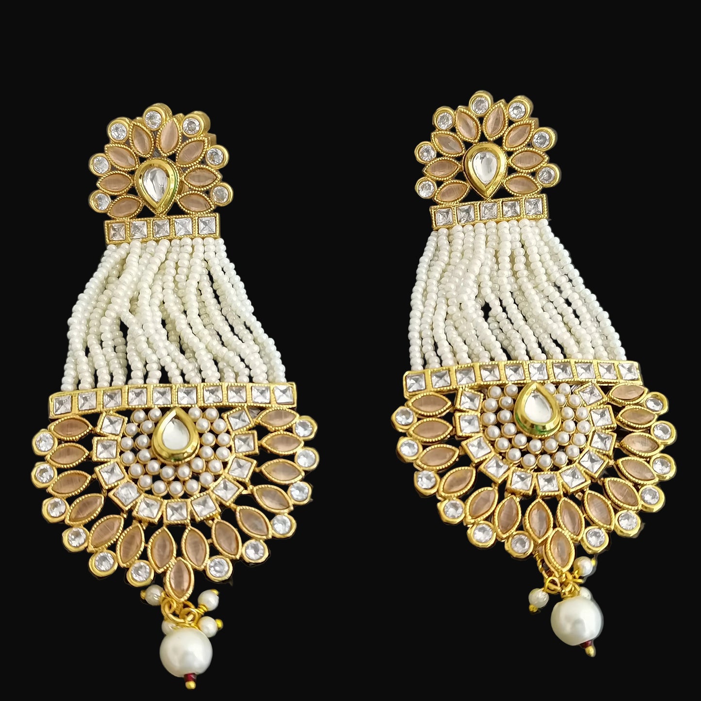 Pair of gold and pearl earrings on a dark background