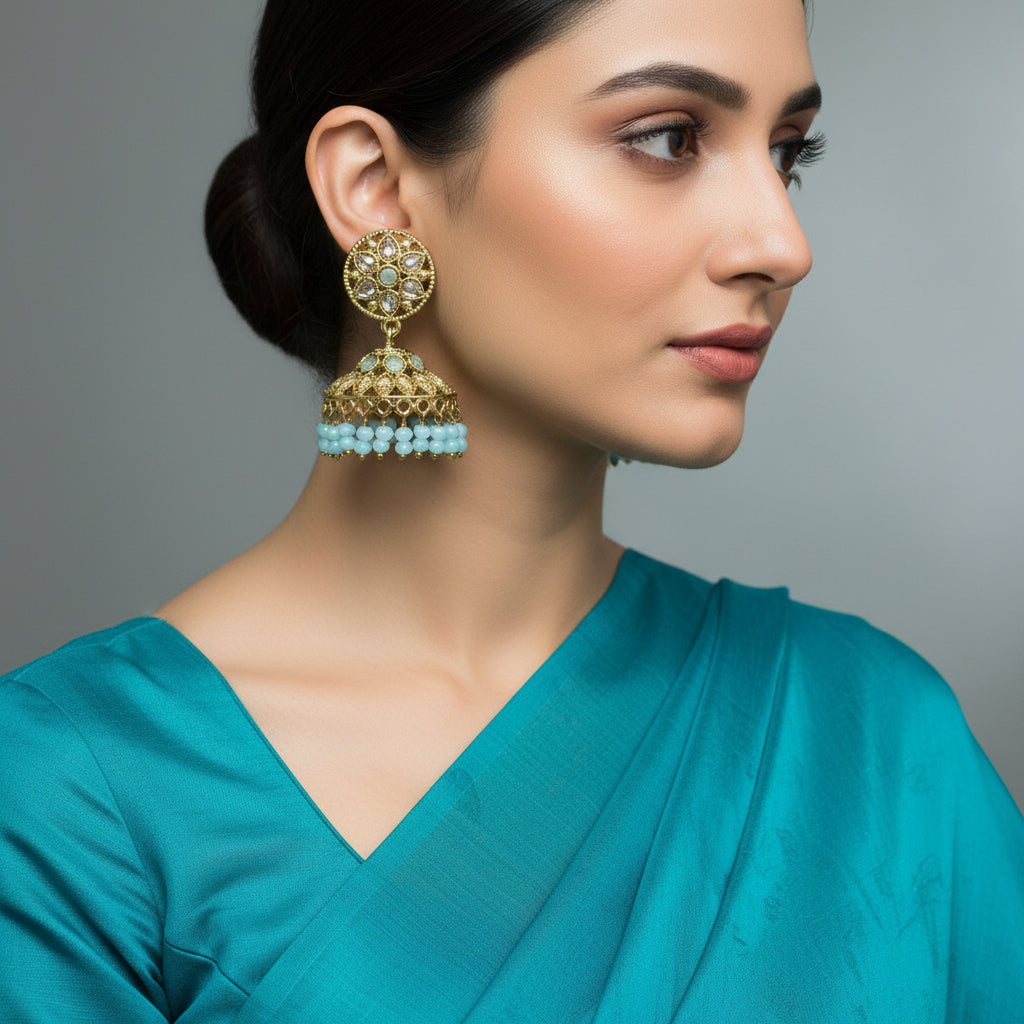 Gold and turquoise earrings on a gray stand with a gray background