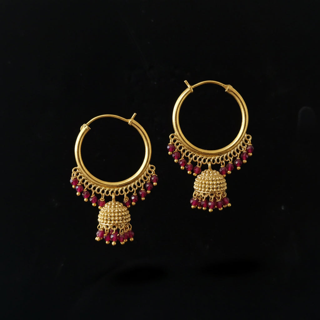 Gold hoop earrings with red gemstones on a black background, branded 'Saheli'.