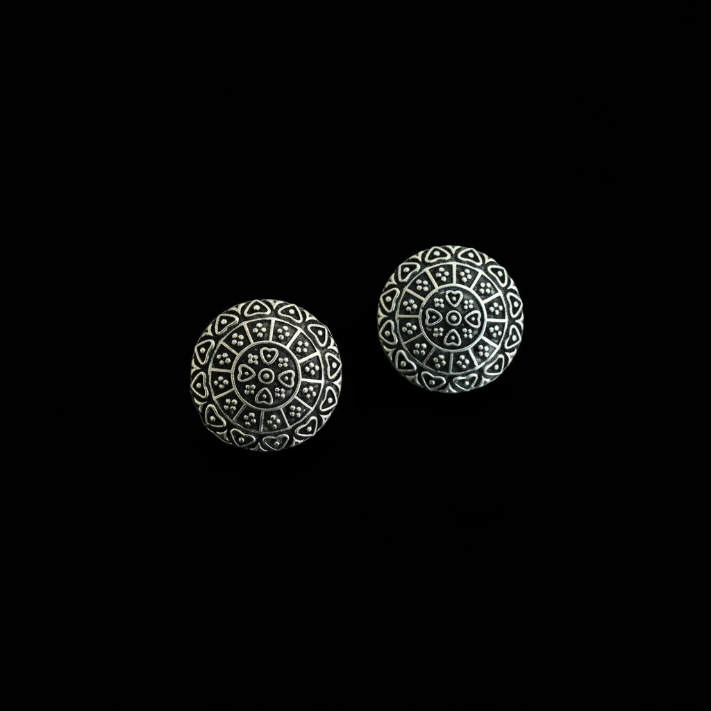 Pair of silver spherical earrings with intricate designs on a dark gray background