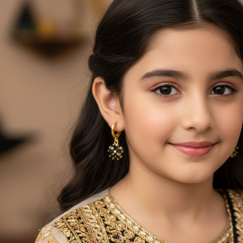 Gold earrings with black stones on a gray background, featuring the brand 'Saheli'.