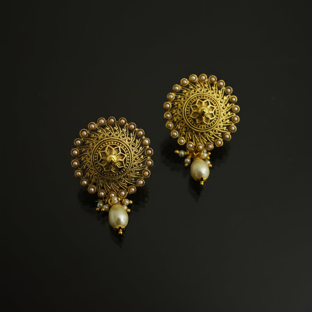 Pair of gold earrings with pearl accents on a black background