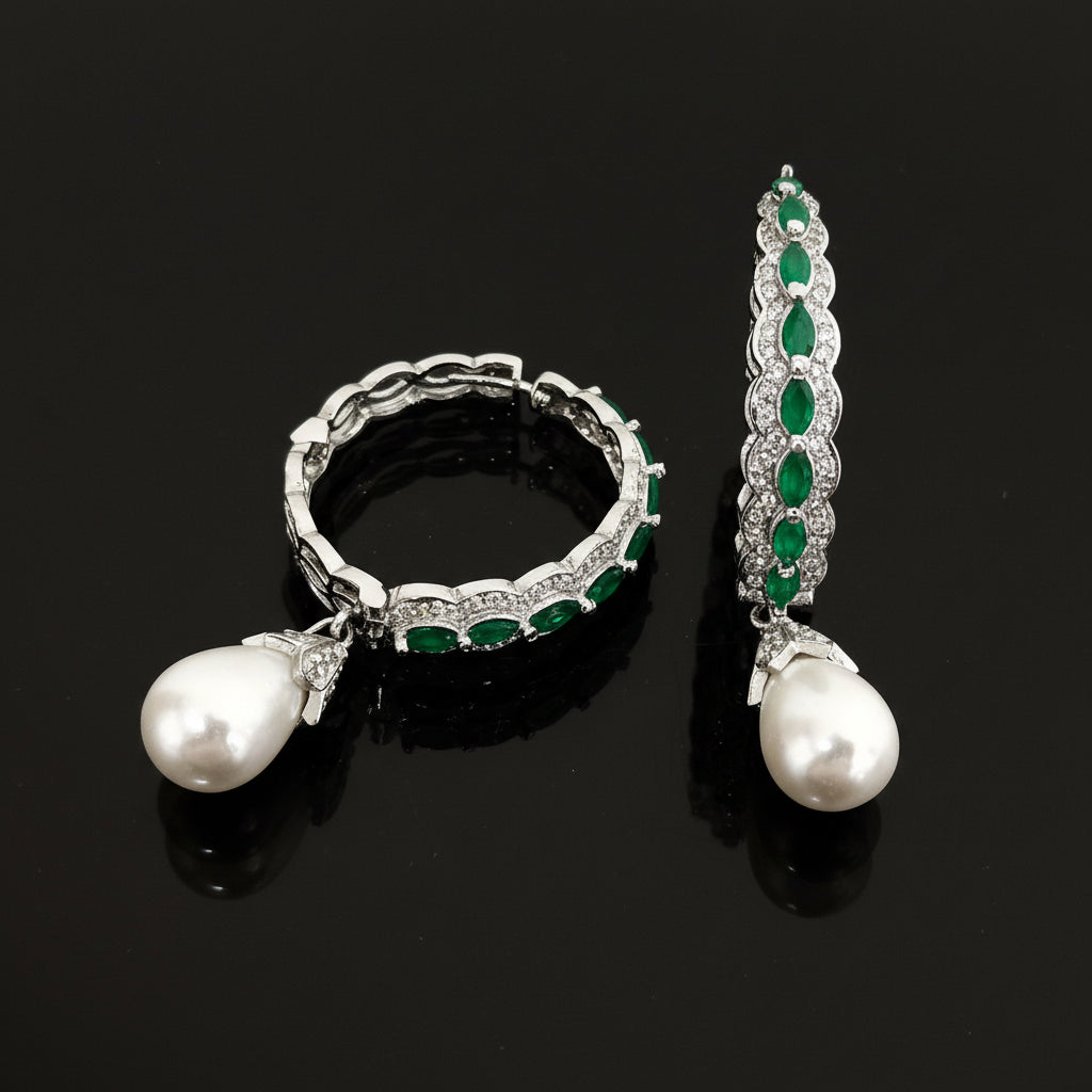 Jewelry set with emerald and pearl earrings on a dark background, featuring the brand 'Saheli'.