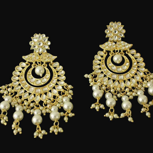 Pair of gold and pearl earrings on a dark background
