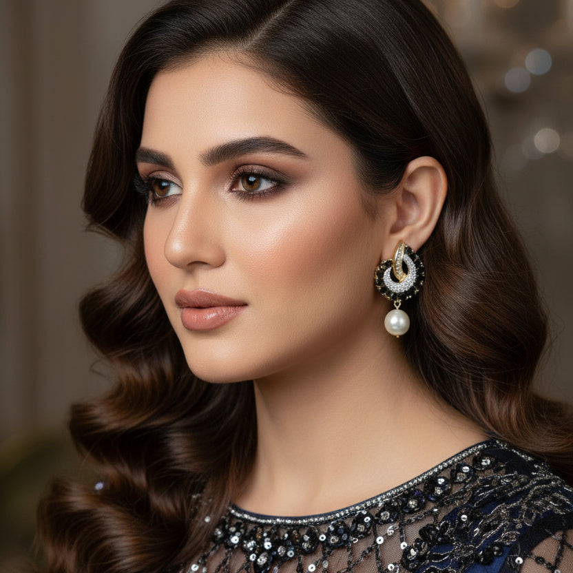 Pair of earrings with pearls and gemstones on a dark background, branded 'SAHELI'.