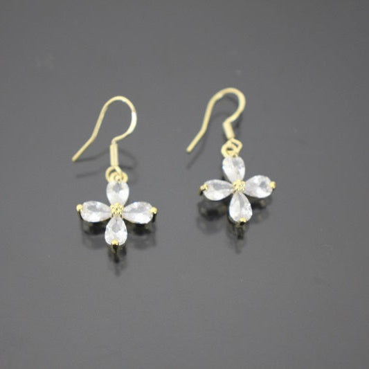 Gold earrings with clear gemstones on a dark gray background