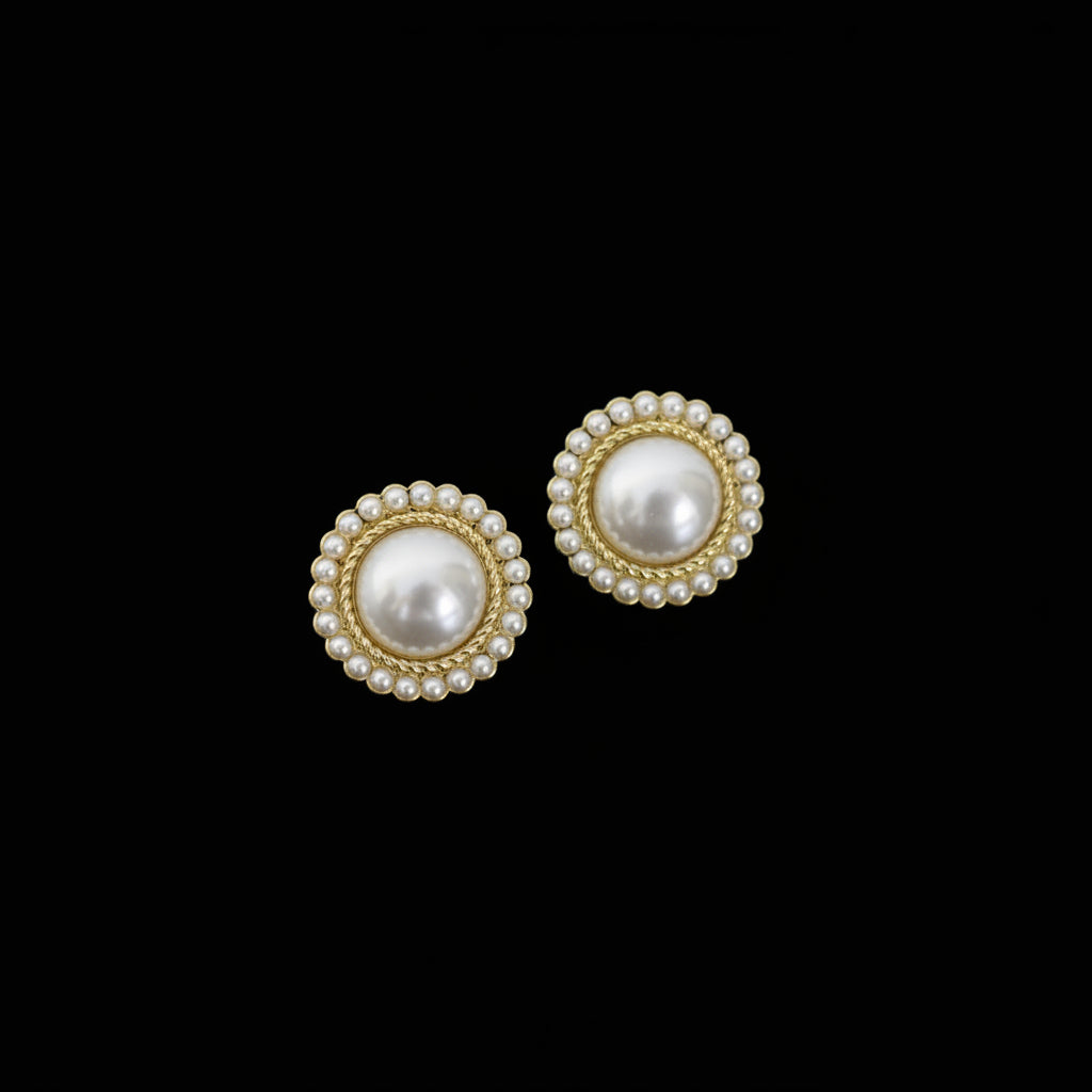 Pair of pearl earrings with gold accents on a dark background