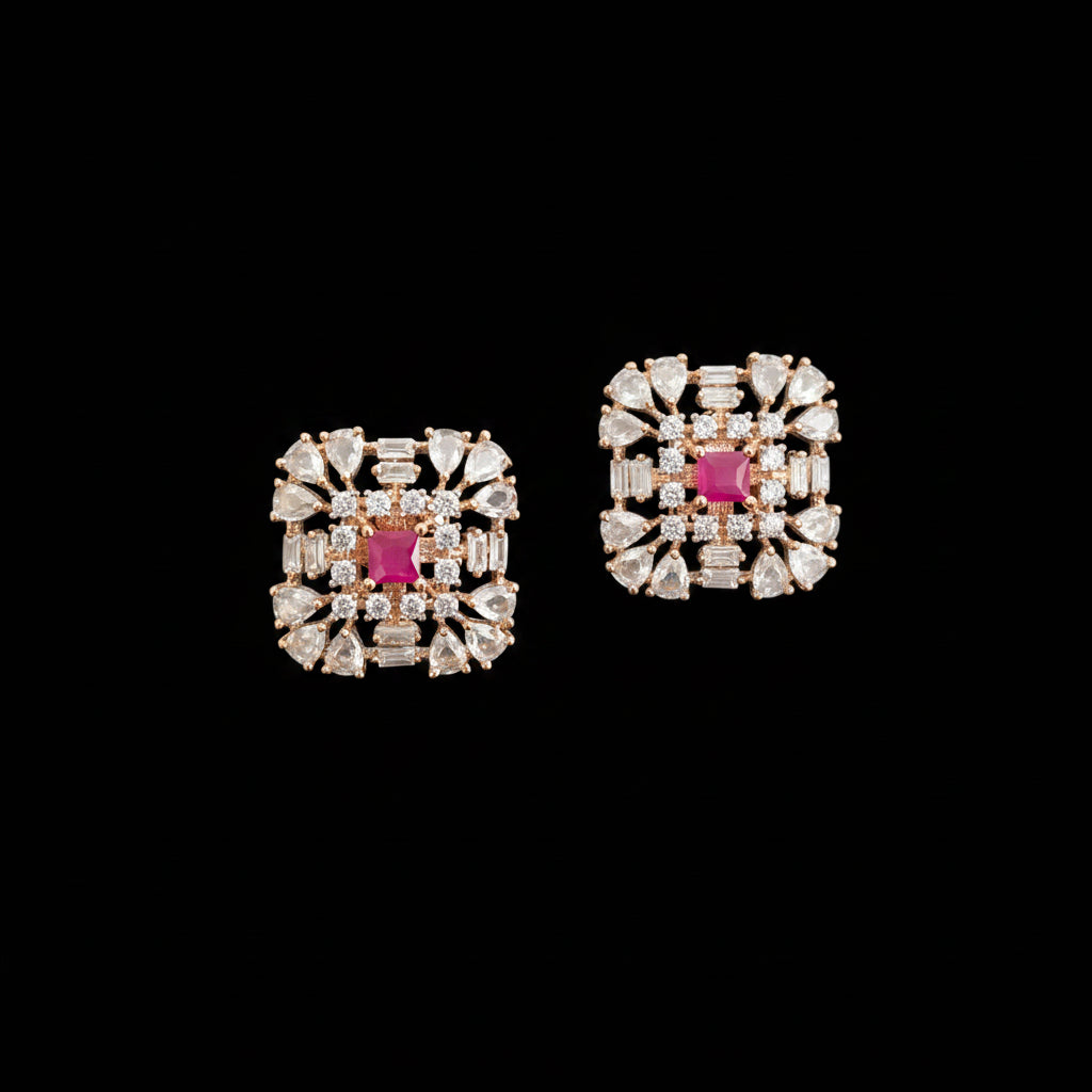 Pair of gold earrings with pink gemstones on a gray background, featuring the brand 'Saheli'.