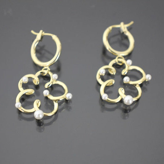 Gold earrings with pearl-like beads on a dark background